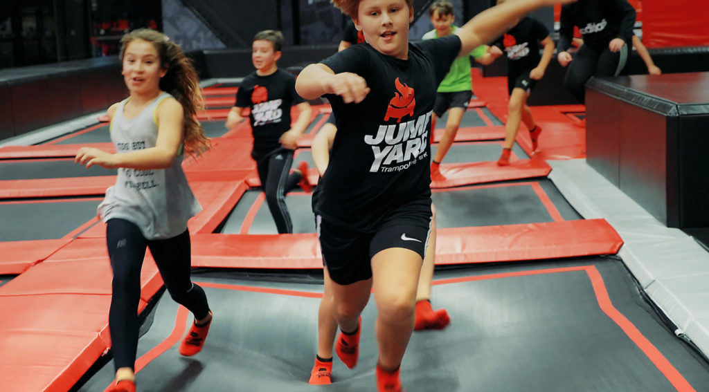 Barn som springer på studsmattor på JumpYard