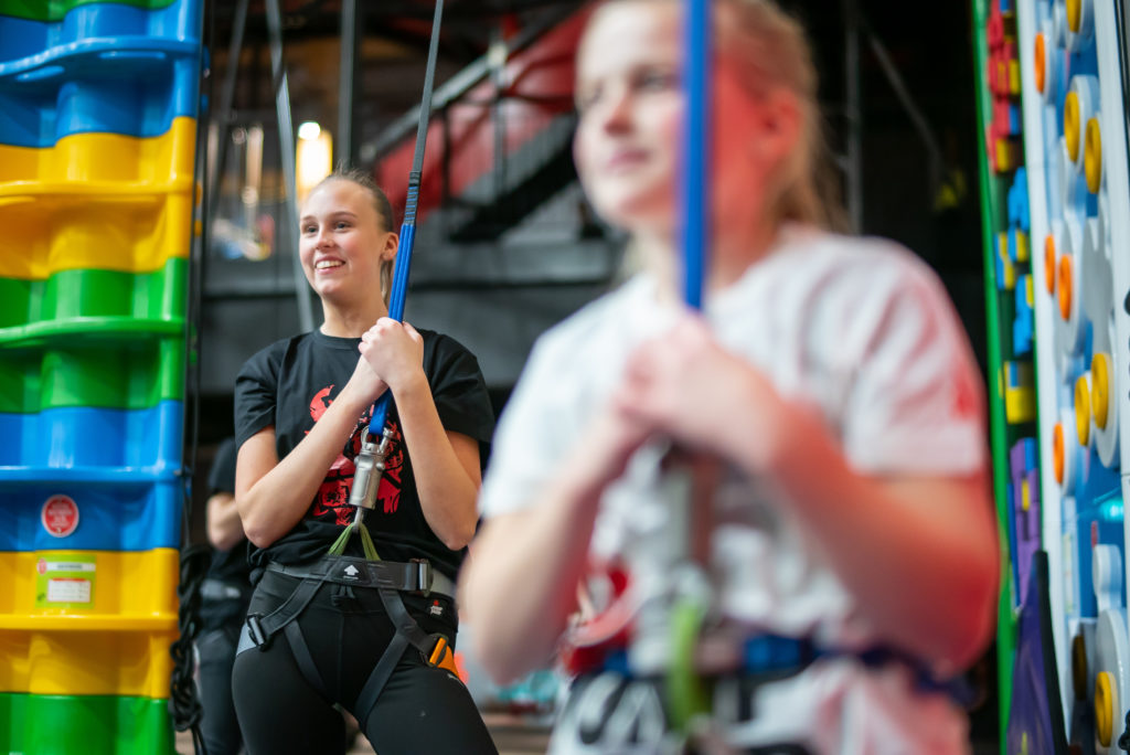 Två tjejer står vid Clip 'N Climb, säkrade och redo att börja klättra.